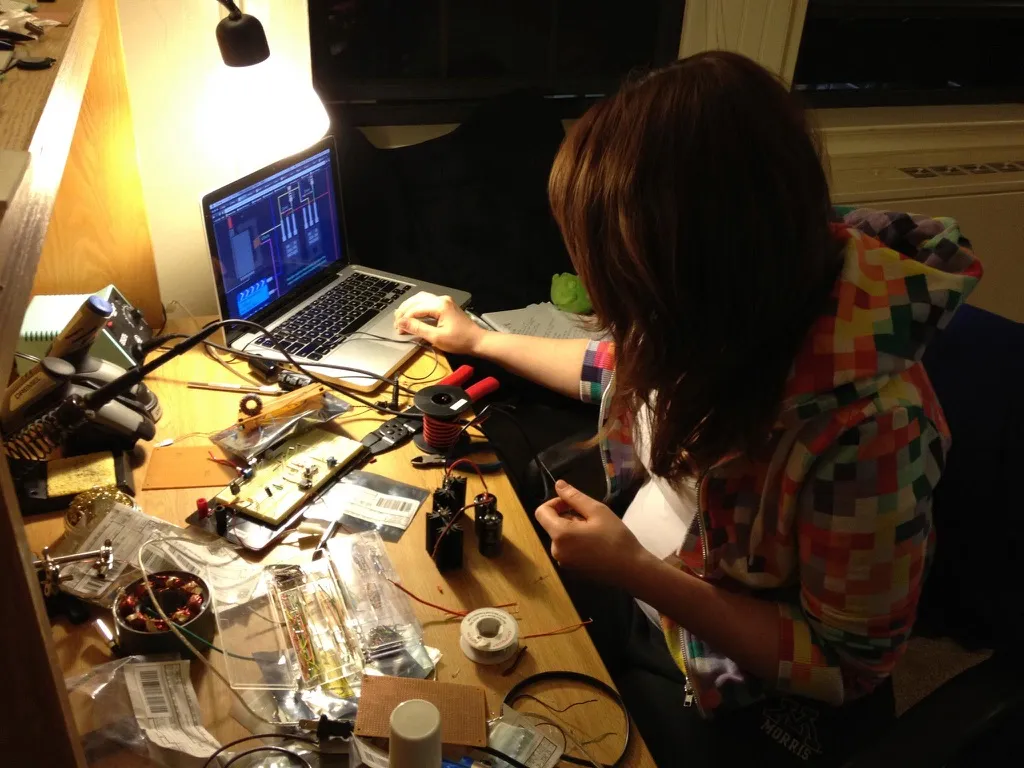 Ingrid working with electronics and a laptop at a workbench