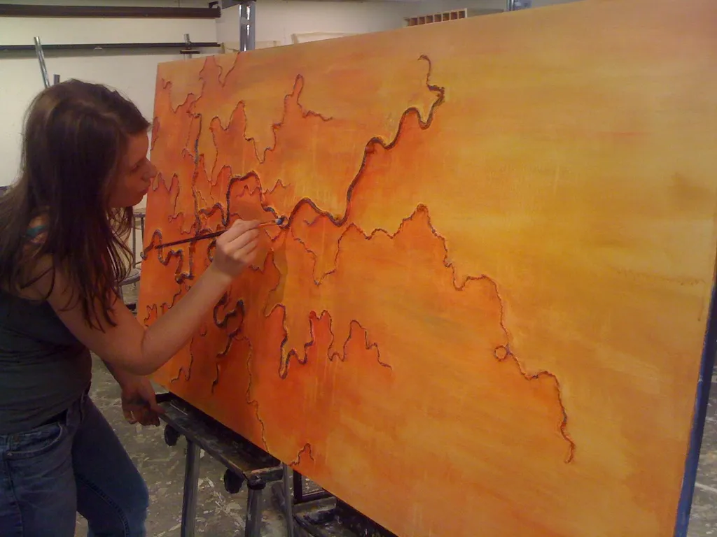 Ingrid painting a large orange abstract artwork in a studio