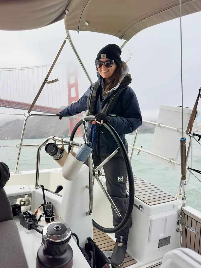 Ingrid at the helm of a sailboat near the Golden Gate Bridge